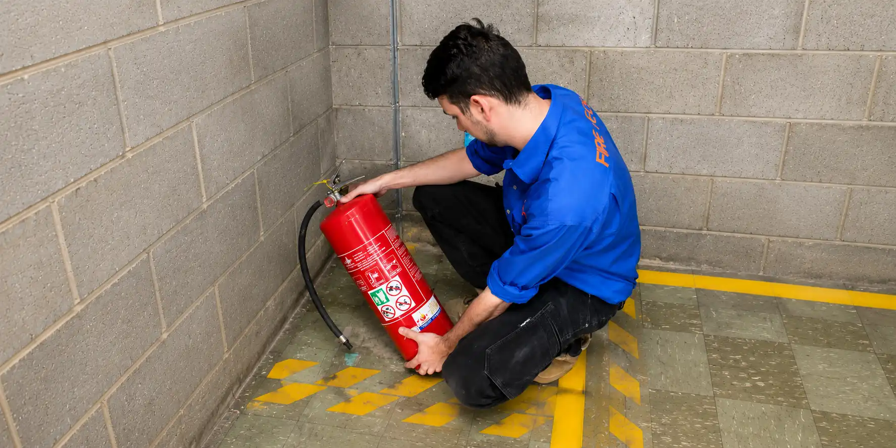Technician inspecting fire extinguisher placement and condition onsite.