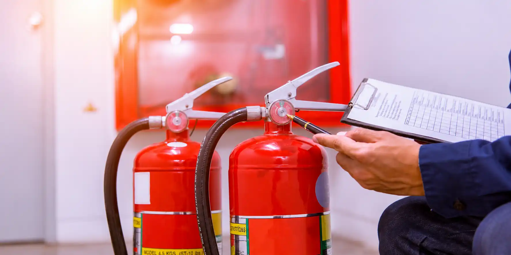 Technician inspecting fire extinguishers with checklist during safety maintenance.