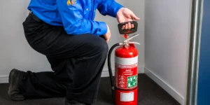 Technician testing portable fire extinguisher during scheduled safety service.