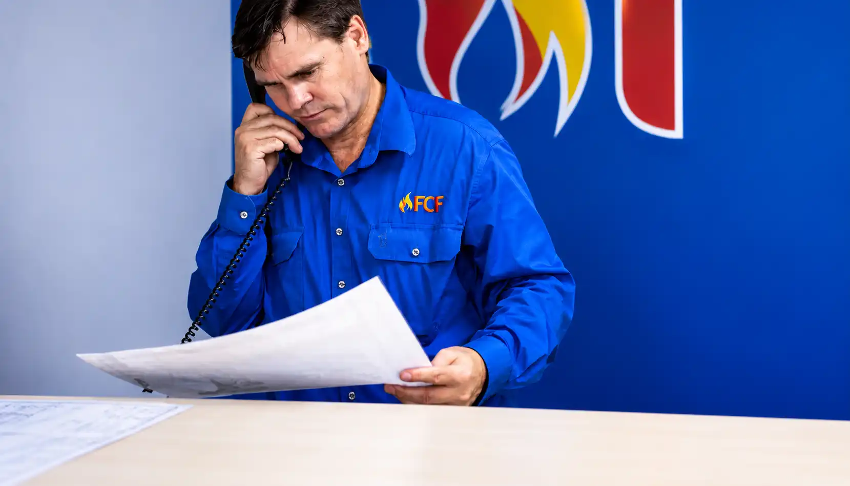 Technician reviewing plans during fire extinguisher inspection and safety assessment.